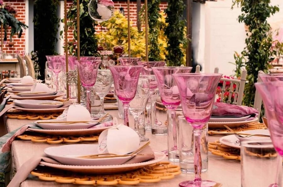 Decoración de mesas para eventos de gala en algarabiafiestas.com, con candelabros de cristal, centros de mesa florales y mobiliario transparente bajo iluminación neón profesional.