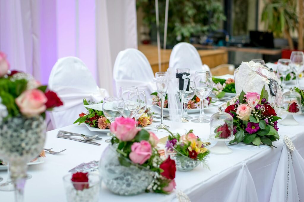 Diseño floral exclusivo de algarabiafiestas.com para evento de gala, con un majestuoso árbol de flores de cerezo, centros de mesa florales vibrantes y candelabros de cristal sobre mesas con mantelería oscura.