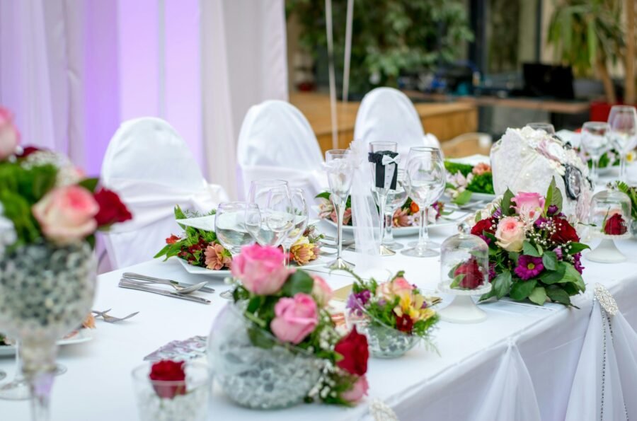 Diseño floral exclusivo de algarabiafiestas.com para evento de gala, con un majestuoso árbol de flores de cerezo, centros de mesa florales vibrantes y candelabros de cristal sobre mesas con mantelería oscura.
